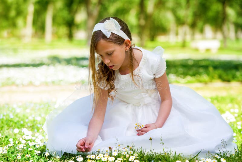 Söt flicka i vita klänningplockningblommor. royaltyfri bild Söt flicka i vita klänningplockningblommor. royaltyfri bild