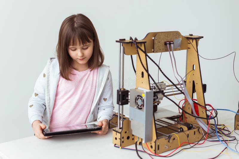 Söt flicka med 3d-tryckta slutare tittar på sin 3d-skrivare när den skriver ut sin 3D-modell.