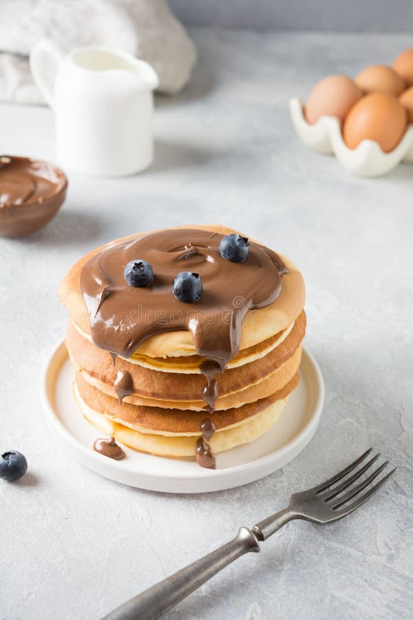 Söt hemlagad bunt av pannkakor med choklad och blåbäret på den vita tabellen arkivfoton Söt hemlagad bunt av pannkakor med choklad och blåbäret på den vita tabellen arkivfoton