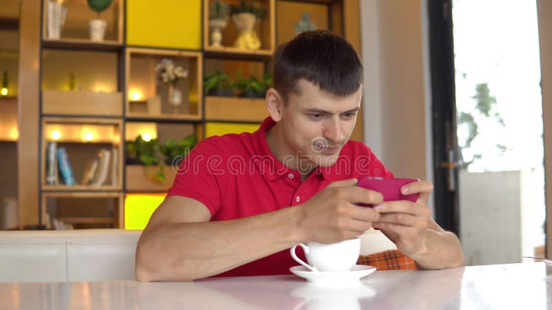 Söt kopp för giffel för bakgrundsavbrottskaffe Leklek för ung man på mobiltelefonen lager videofilmer