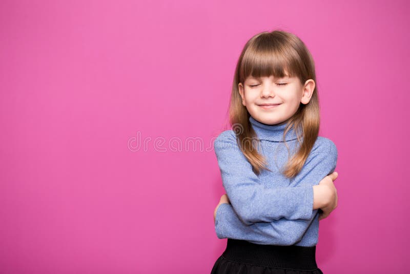 Söt liten flicka gnäller sig själv som leende och glad. arkivbild