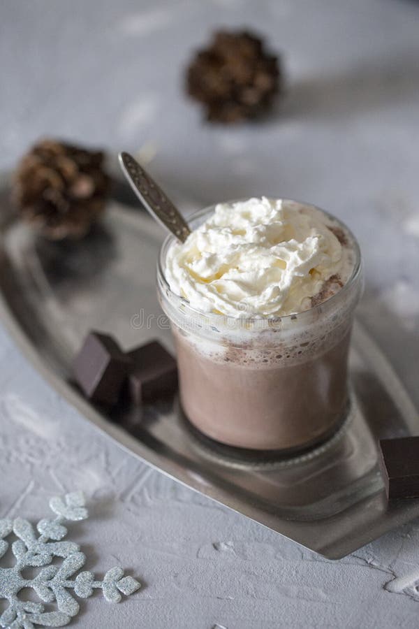 Söt varm choklad med kräm och skivan av mörk choklad i exponeringsglas på magasinet på konkret bakgrund arkivfoton Söt varm choklad med kräm och skivan av mörk choklad i exponeringsglas på magasinet på konkret bakgrund arkivfoton