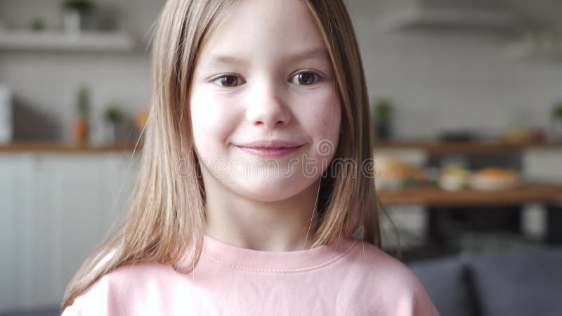 Söt, ynklig liten flicka som tittar på kameran i hemmet, nära ansiktet porträtt. stock video
