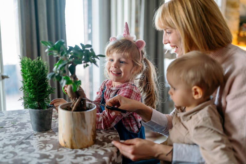 Söta barn som hjälper modern att ta hand om växter. Mamma och hennes barn som ägnar sig åt trädgårdsskötsel hemma. familjehobbykoncept.