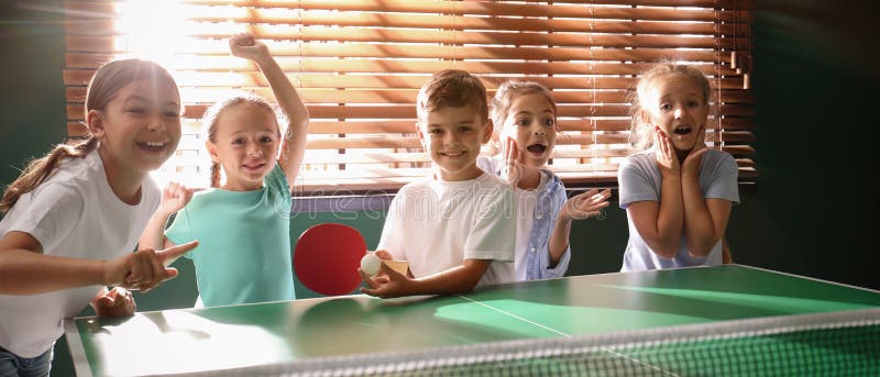 Süße Kinder spielen Tischtennis drinnen. Banner stockfotos