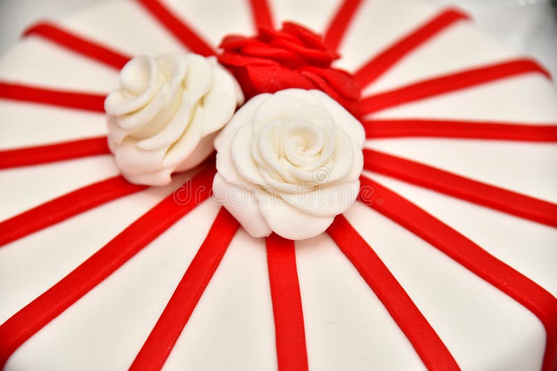 Süße Kuchen in Form von roten Rosen verzieren die Hochzeitstorte mit den dekorativeren Zweigen der weißen Creme stockfoto