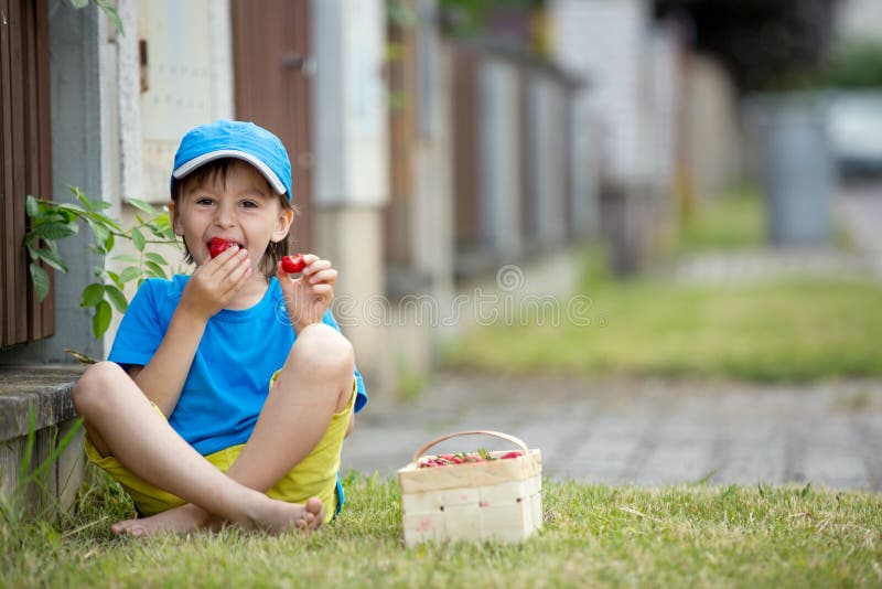 Süßes entzückendes kleines Kind, Junge, der Erdbeeren, Sommerzeit isst lizenzfreies stockbild Süßes entzückendes kleines Kind, Junge, der Erdbeeren, Sommerzeit isst lizenzfreies stockbild