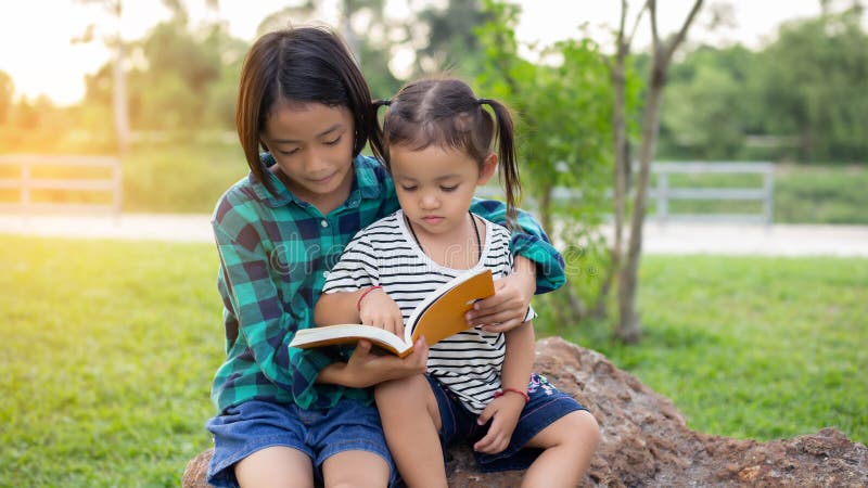 Süßes kleines Mädchen, das in Parkhaus ein Buch über Baum liest lizenzfreies stockfoto