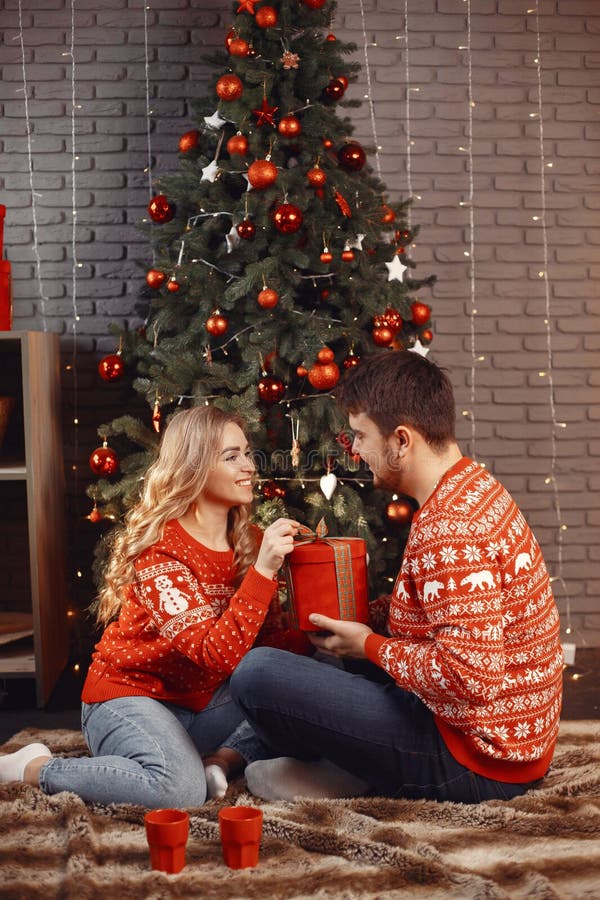 Süßes Paar zu Hause neben Weihnachtsbaum sitzend stockbild
