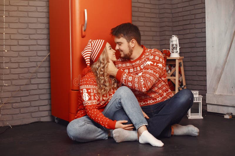 Süßes Paar zu Hause neben Weihnachtsbaum sitzend stockfotografie