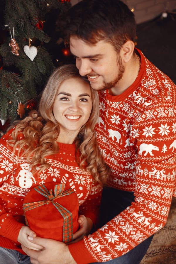 Süßes Paar zu Hause neben Weihnachtsbaum sitzend stockfotografie