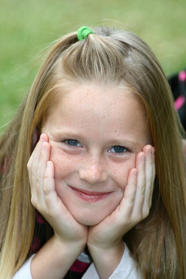 A portrait of a white caucasian kid holding her head in her hands. A portrait of a white caucasian kid holding her head in her hands