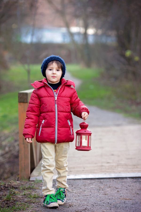 Słodki dziecko, trzyma czerwonego lampion w parku na pogodnym zima d