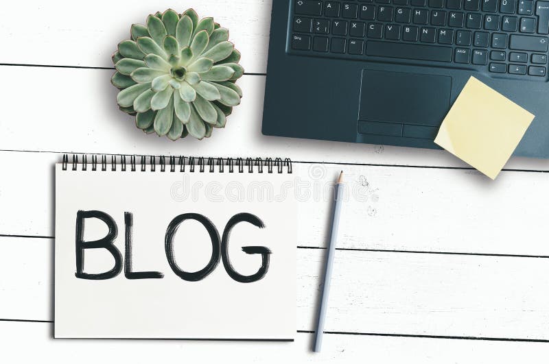 Słowo blog na ślimakowatym notepad na nieociosanym białym biurku z laptopem i puszkującą rośliną zdjęcie stock Słowo blog na ślimakowatym notepad na nieociosanym białym biurku z laptopem i puszkującą rośliną zdjęcie stock