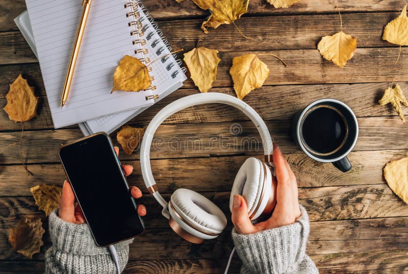 Headphones with autumn dry leaves, cuo of coffee and notepads on rustic wooden background. Top view. Flat lay. Headphones with autumn dry leaves, cuo of coffee and notepads on rustic wooden background. Top view. Flat lay