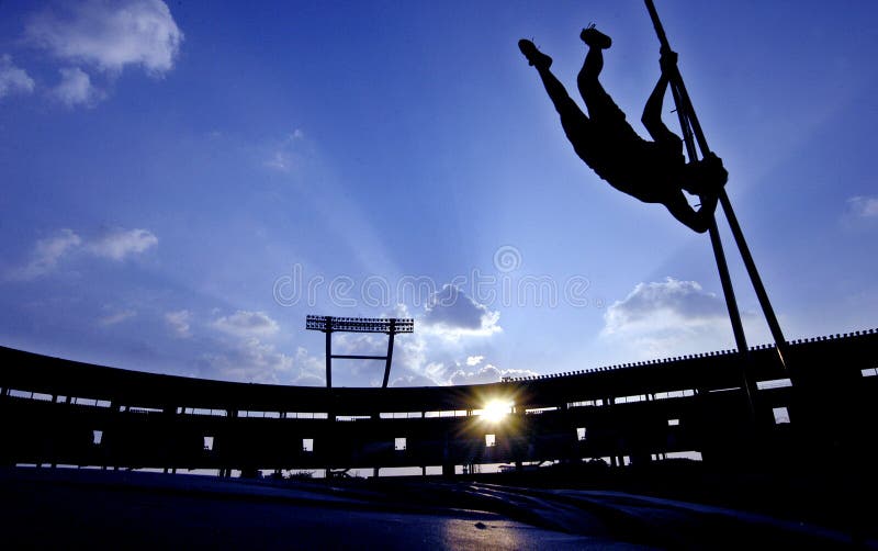 An athlete attempt a pole vault while silhouetted by the sun against a cloudy sky. An athlete attempt a pole vault while silhouetted by the sun against a cloudy sky