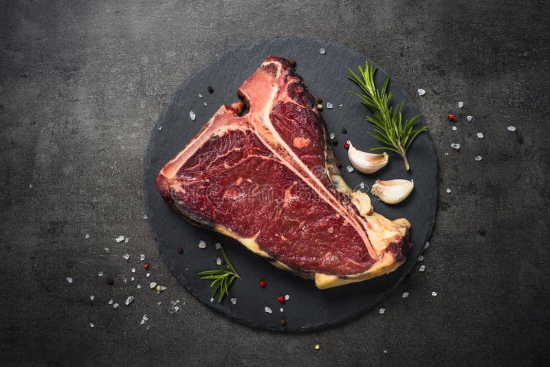 T-bone beef steak on black with spices. 