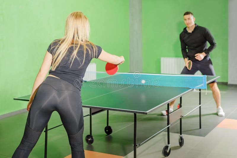 T?nis de mesa o homem e a mulher competem em um jogo do pong do sibilo Competi??o do cavalo