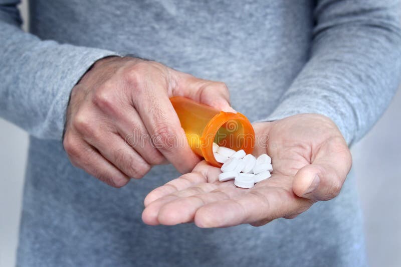 Hands of man holding pill bottle with pills on hand. Hands of man holding pill bottle with pills on hand