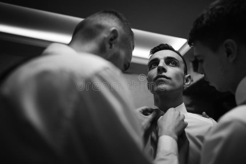 Ta hand om att lägga ut och hjälpa en stilfull groomsman att göra sig redo på morgonen bröllopsförberedelse vänner som har kul royaltyfria bilder Ta hand om att lägga ut och hjälpa en stilfull groomsman att göra sig redo på morgonen bröllopsförberedelse vänner som har kul royaltyfria bilder