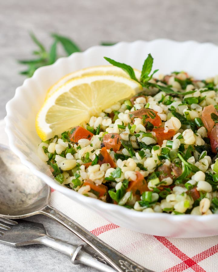 Tabboulehsalade met bulgur, tomaten, peterselie, groene ui en munt in plaat op grijze steenlijst royalty-vrije stock afbeeldingen Tabboulehsalade met bulgur, tomaten, peterselie, groene ui en munt in plaat op grijze steenlijst royalty-vrije stock afbeeldingen