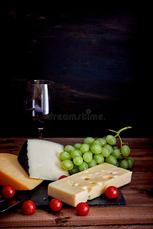 Tabela com queijos e vidro de vinho diferentes no fundo escuro fotos de stock royalty free Tabela com queijos e vidro de vinho diferentes no fundo escuro fotos de stock royalty free