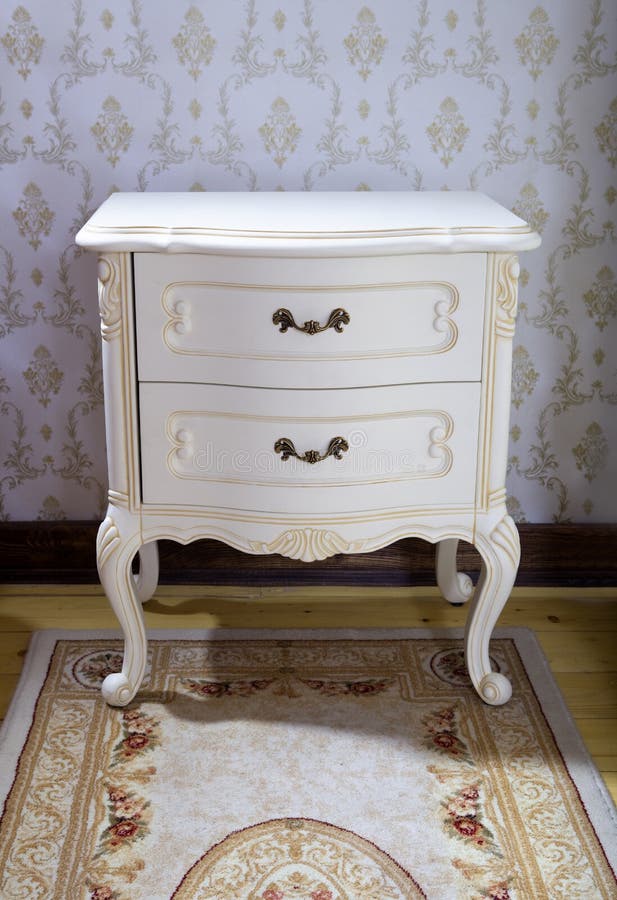 Detail of vintage wooden bedside table with three drawers on rug. Detail of vintage wooden bedside table with three drawers on rug