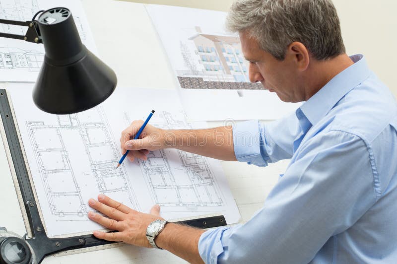 Tabela de Working At Drawing do arquiteto imagem de stock Tabela de Working At Drawing do arquiteto imagem de stock