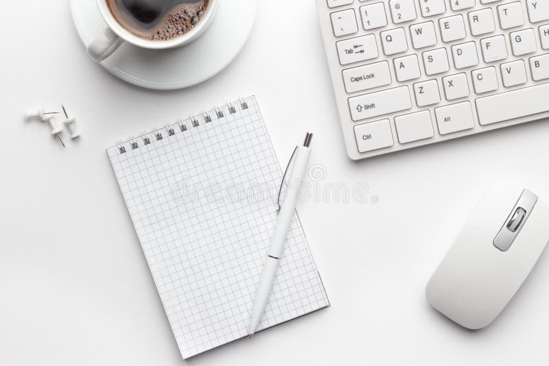 Tabela do escritório com o copo do bloco de notas, do computador e de café
