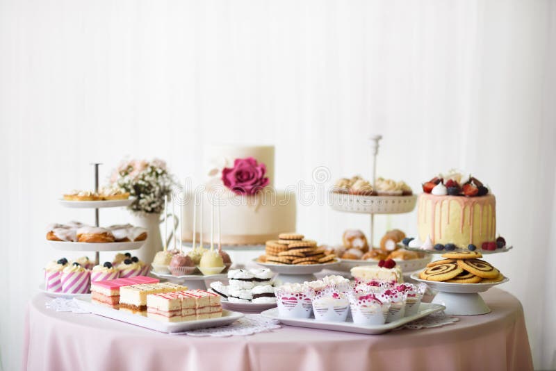 Tabella con i carichi dei dolci, dei bigné, dei biscotti e dei cakepops fotografie stock Tabella con i carichi dei dolci, dei bigné, dei biscotti e dei cakepops fotografie stock