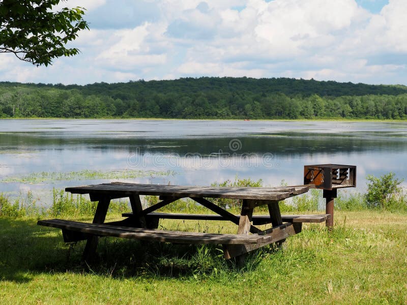 Tabella Di Picnic Di Lakeside E Supporto Del Barbecue Immagine Stock
