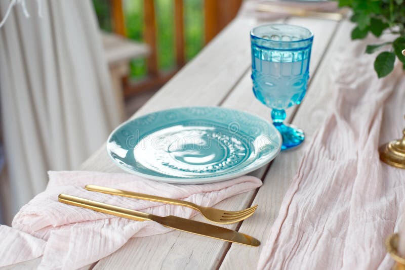 Tabelle für Gäste, verziert mit Kerzen, gedient mit Tischbesteck und Tonware und mit einer blauen Platte der Tischdecke bedeckt u lizenzfreie stockfotos Tabelle für Gäste, verziert mit Kerzen, gedient mit Tischbesteck und Tonware und mit einer blauen Platte der Tischdecke bedeckt u lizenzfreie stockfotos
