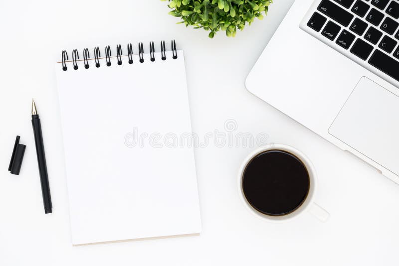 Tabla blanca del escritorio de oficina con la página en blanco del cuaderno con la pluma, el ordenador portátil y el café Visi?n fotografía de archivo libre de regalías Tabla blanca del escritorio de oficina con la página en blanco del cuaderno con la pluma, el ordenador portátil y el café Visi?n fotografía de archivo libre de regalías