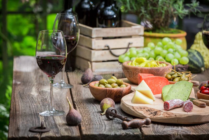 Tabla del jardín con el queso, vino rojo por la tarde imágenes de archivo libres de regalías Tabla del jardín con el queso, vino rojo por la tarde imágenes de archivo libres de regalías