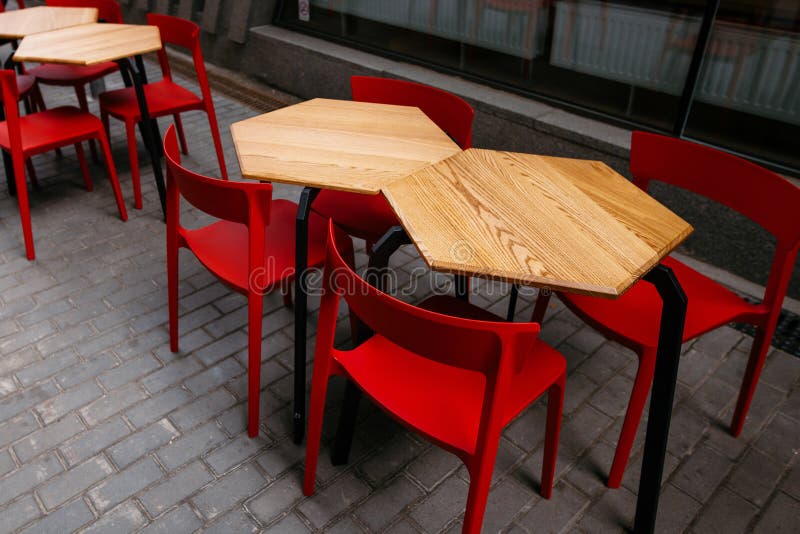 Tablas de madera elegantes y sillas de acero rojas en calle de la ciudad agujas fotografía de archivo Tablas de madera elegantes y sillas de acero rojas en calle de la ciudad agujas fotografía de archivo