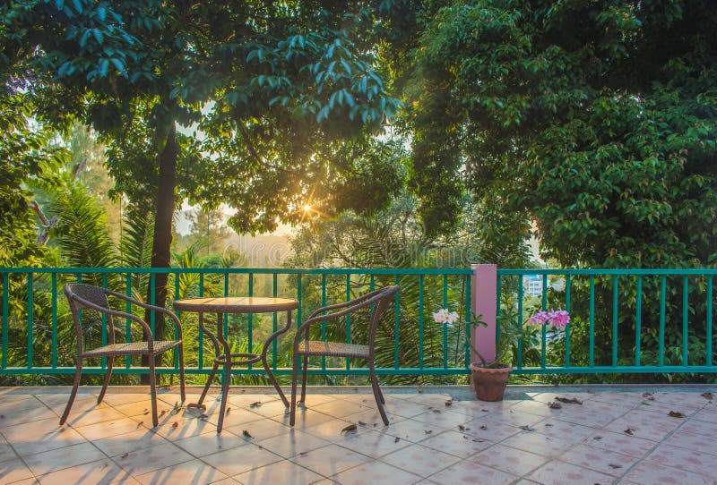 Table and Chair on Wood Deck in the Garden with Sunset Stock Photo