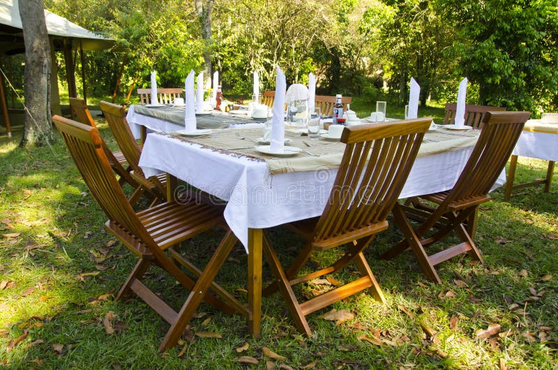Table de salle à manger mise dans le jardin luxuriant image libre de droits Table de salle à manger mise dans le jardin luxuriant image libre de droits