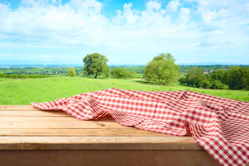 Empty wooden table with tablecloth over summer meadow background. Empty wooden table with tablecloth over summer meadow background