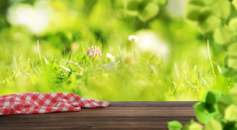 Empty wooden table with checkered napkin outdoors, space for design. Summer picnic. Empty wooden table with checkered napkin outdoors, space for design. Summer picnic