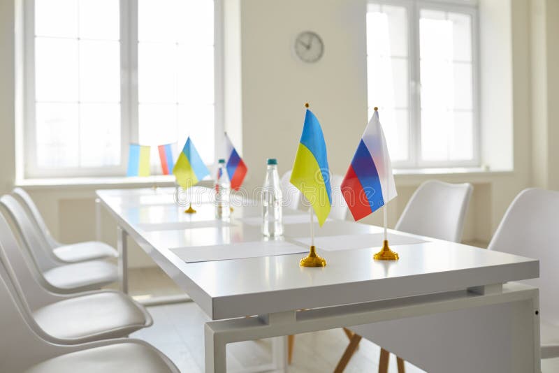 Empty chairs at table with flags of Ukraine and Russia at negotiation on ceasing bombing, stopping genocide, troop withdrawal, ending war, restoring peace, future Crimea and Donbass conflict resolving. Empty chairs at table with flags of Ukraine and Russia at negotiation on ceasing bombing, stopping genocide, troop withdrawal, ending war, restoring peace, future Crimea and Donbass conflict resolving