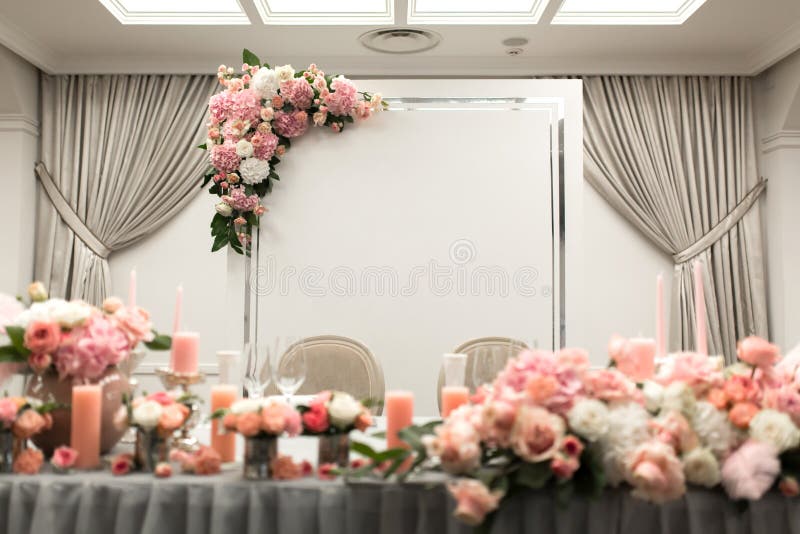 The table for the newlyweds is decorated with fresh flowers in the restaurant. Square lighting and spotlights.