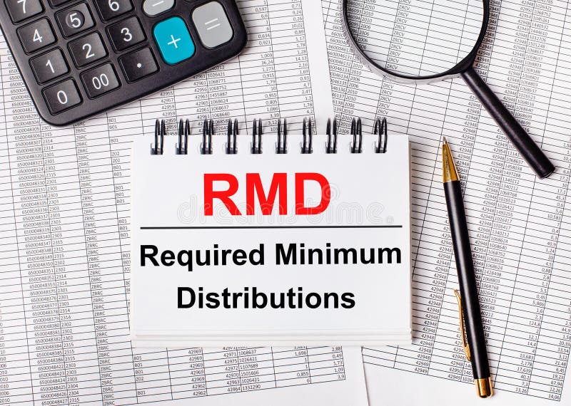 On the table are reports, a magnifying glass, a calculator, a pen, and a white notebook with the text RMD Required Minimum. Distributions royalty free stock photos