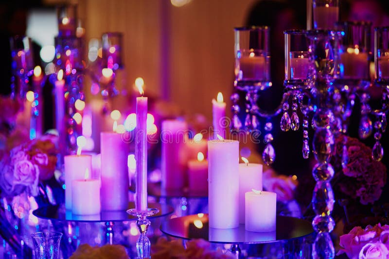 Table set with candles for a festive event, party or wedding reception, in purple light royalty free stock image