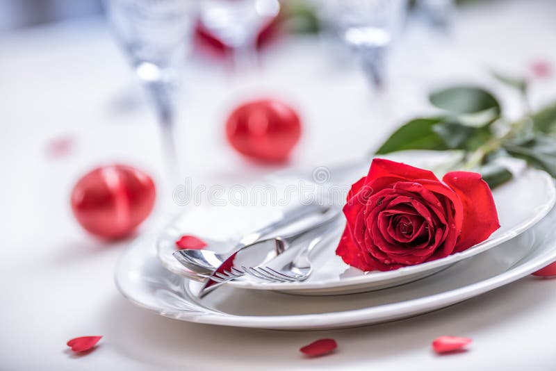 Table setting for valentines or wedding day with red roses. Romantic table setting for two with roses plates cups and cutlery