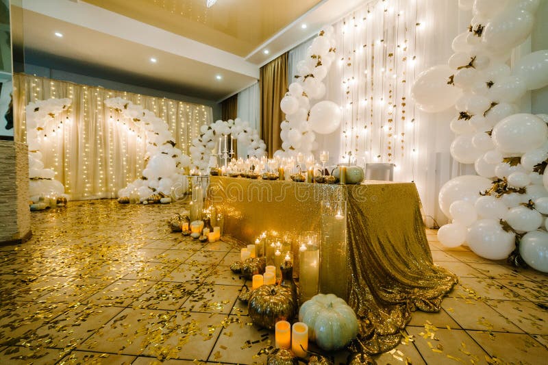 Table setting for a wedding. Decorated arch for wedding ceremony. White balloons, candles, autumn leaves and small pumpkins. Autumn location and Halloween decor. Table setting for a wedding. Decorated arch for wedding ceremony. White balloons, candles, autumn leaves and small pumpkins. Autumn location and Halloween decor.