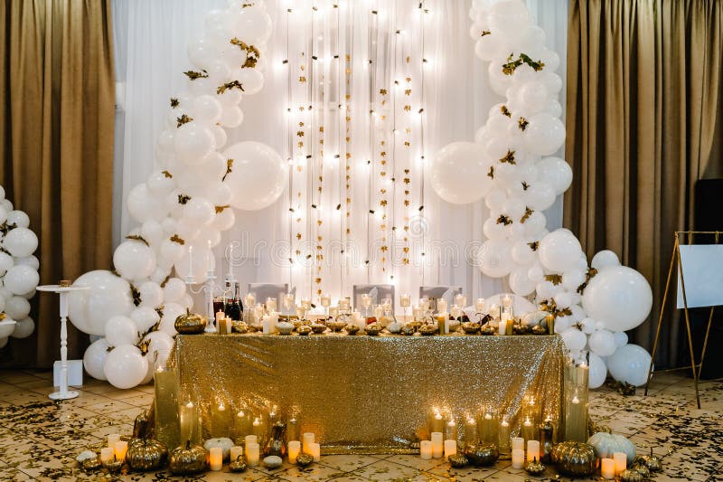 Table setting for wedding. Decorated arch for wedding ceremony. White balloons, candles, autumn leaves and small pumpkins. Autumn location and Halloween decor