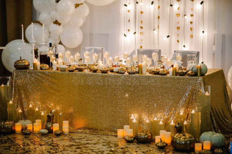 Table setting for wedding. Decorated arch for wedding ceremony. White balloons, candles, autumn leaves and small pumpkins. Autumn location and Halloween decor