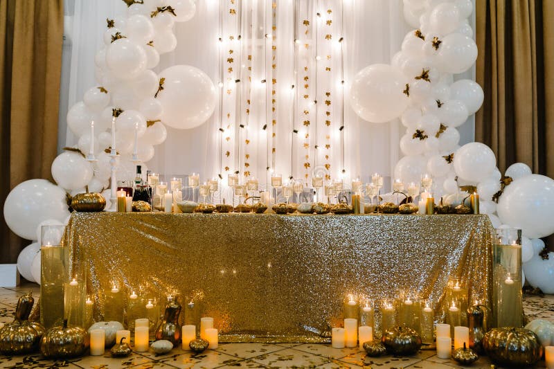 Table setting for wedding. Decorated arch for wedding ceremony. White balloons, candles, autumn leaves and small pumpkins. Autumn location and Halloween decor