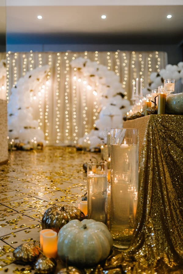 Table setting for wedding. Decorated arch for wedding ceremony. White balloons, candles, autumn leaves and small pumpkins. Autumn location and Halloween decor.