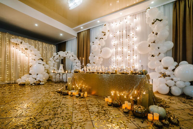 Table setting for wedding. Decorated arch for wedding ceremony. White balloons, candles, autumn leaves and small pumpkins. Autumn location and Halloween decor.